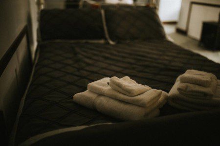 Freshly folded towels on a dark quilted bed in a cozy Fairbanks Alaska adventure treehouse