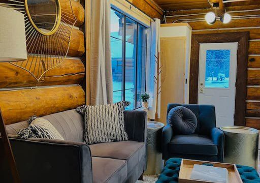 Comfortable sitting area with couch, armchair, and log walls in a Fairbanks Alaska treehouse rental
