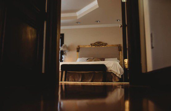 Warm, elegant bedroom with a classic bed frame viewed from doorway in a Fairbanks Alaska adventure lodge