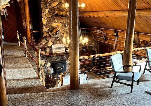 Wooden lodge interior with loft seating, stone fireplace, and taxidermy decor in Fairbanks, Alaska