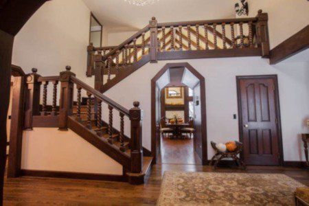Spacious lodge entry with wooden staircase, decorative railing, and hallway view in Fairbanks Alaska