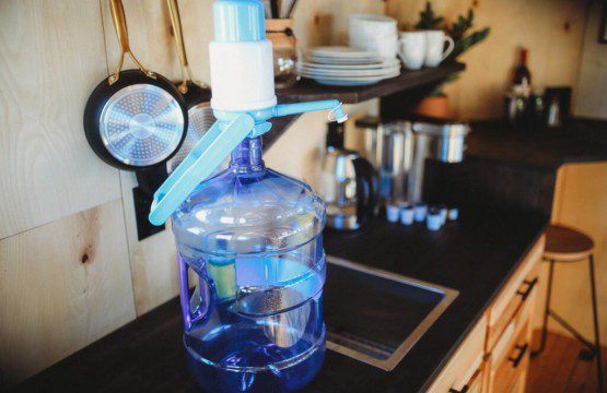 Rustic kitchen with water dispenser, hanging pans, and open shelving in a Fairbanks Alaska treehouse rental