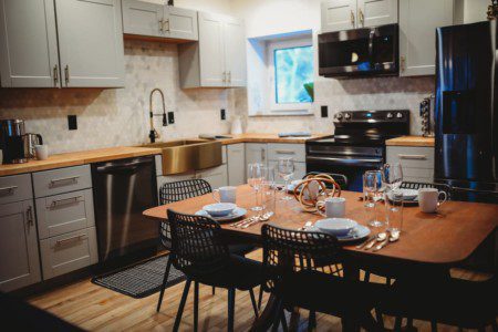 Contemporary kitchen with gold sink, wood counters, and set dining table in a Fairbanks Alaska treehouse