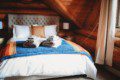 Comfortable bed with colorful blanket and folded towels in a wood-paneled loft in Fairbanks Alaska