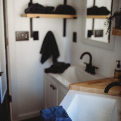 Contemporary bathroom with black fixtures, wood accents, and white sink in a Fairbanks Alaska treehouse rental