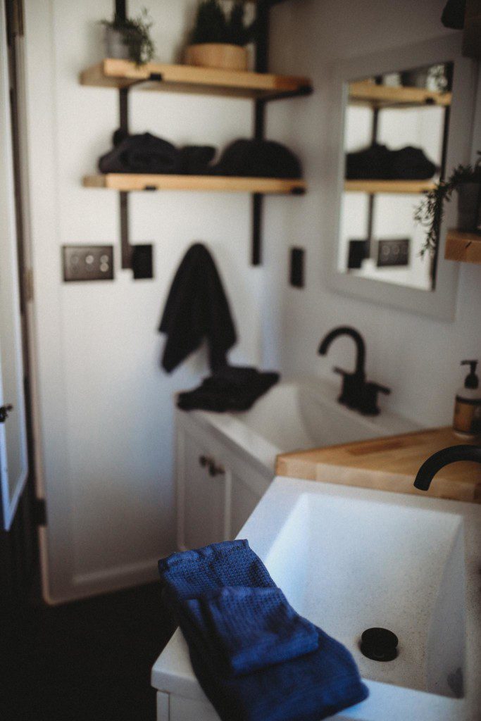 Contemporary bathroom with black fixtures, wood accents, and white sink in a Fairbanks Alaska treehouse rental