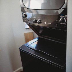 Black stacked washer and dryer in compact laundry nook of Fairbanks treehouse rental