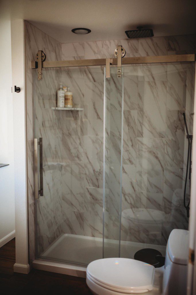 Glass-enclosed shower with marble-style tile in a modern Fairbanks treehouse bathroom