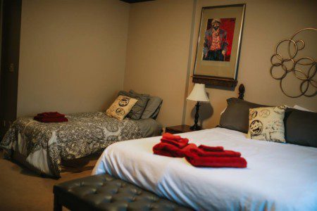 Cozy Fairbanks lodge bedroom with two beds, red towels, pillows, and warm lighting—ideal for wedding or adventure stays