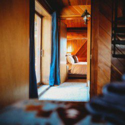 View through wooden hallway into a warmly lit bedroom in a Fairbanks Alaska cabin