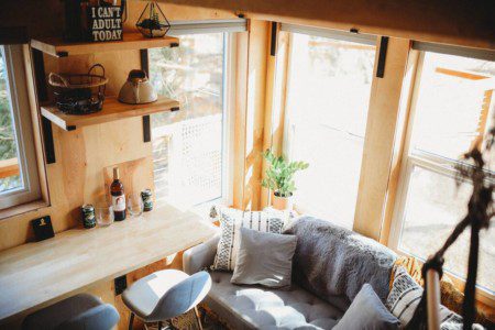 Cozy living area with sofa, bar stools, and large windows inside a Fairbanks Alaska treehouse