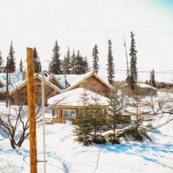 Rustic log lodge surrounded by light snow and trees in Fairbanks, Alaska on a bright day