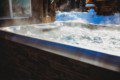 Steaming hot tub outside rustic lodge with snow-covered ground in Fairbanks Alaska