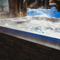 Steaming hot tub outside rustic lodge with snow-covered ground in Fairbanks Alaska