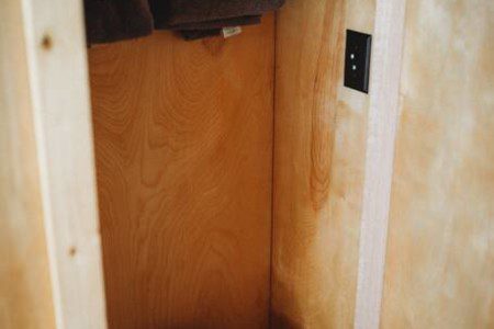 Small wooden bathroom with toilet and hanging towels in a Fairbanks Alaska treehouse