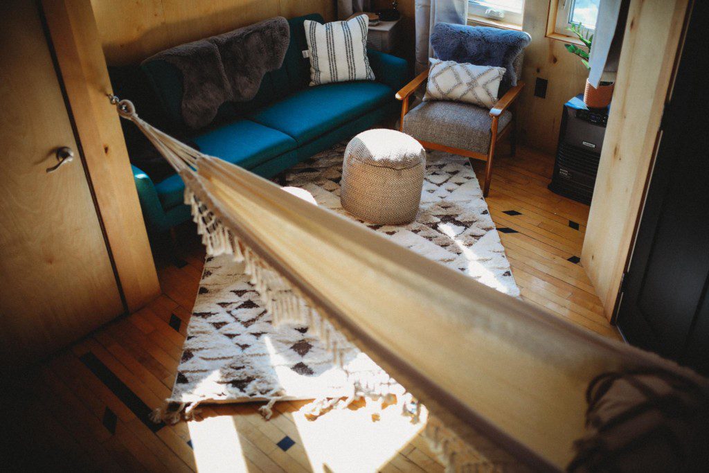 Inviting Fairbanks treehouse interior with hammock, teal sofa, cozy rug, and natural wood decor