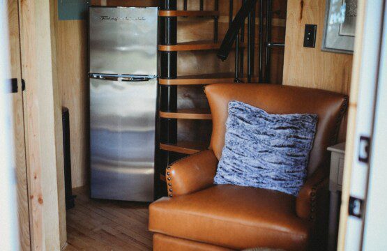 Cozy interior of Fairbanks Alaska treehouse with spiral staircase, leather chair, and loft netting