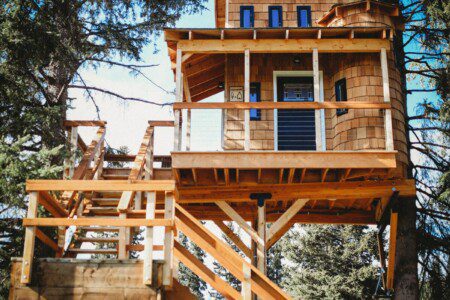 Elevated wooden treehouse with staircase surrounded by trees in Fairbanks, Alaska