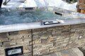 Bubbling outdoor hot tub with stone siding in a snowy Fairbanks Alaska forest setting