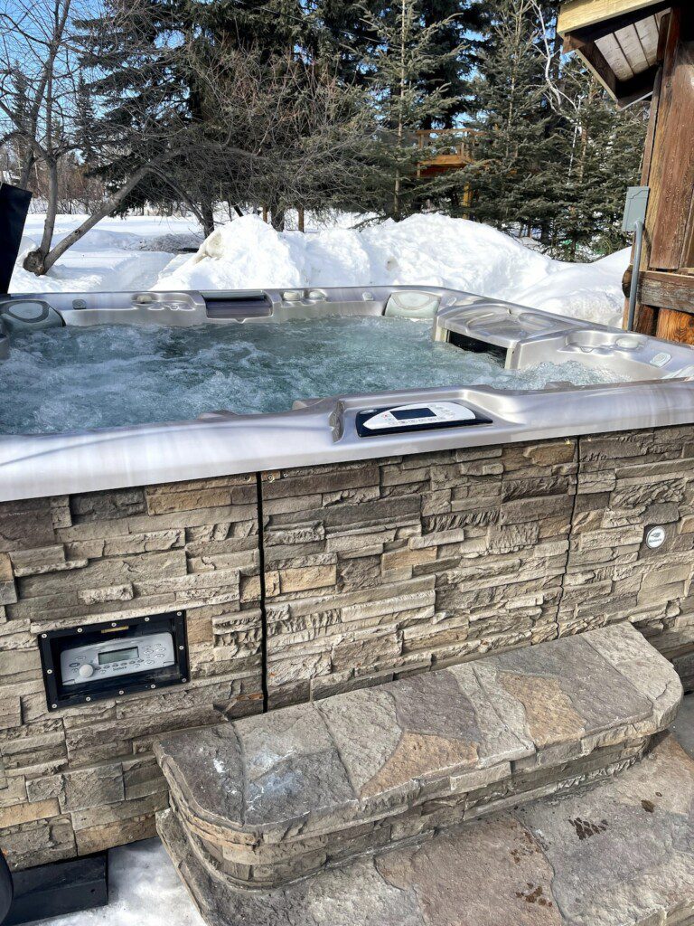 Bubbling outdoor hot tub with stone siding in a snowy Fairbanks Alaska forest setting