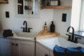 Modern double-sink bathroom with black fixtures and wood shelving in a Fairbanks Alaska treehouse rental.