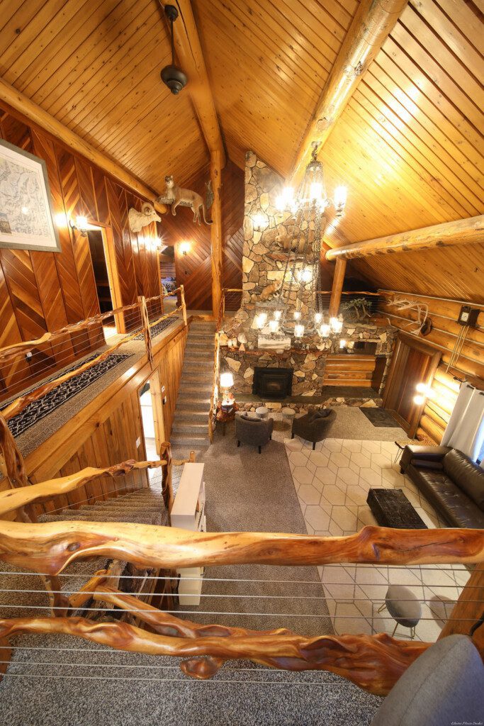 Cozy log cabin living room with stone fireplace, modern sofa, and wood carvings in Fairbanks Alaska