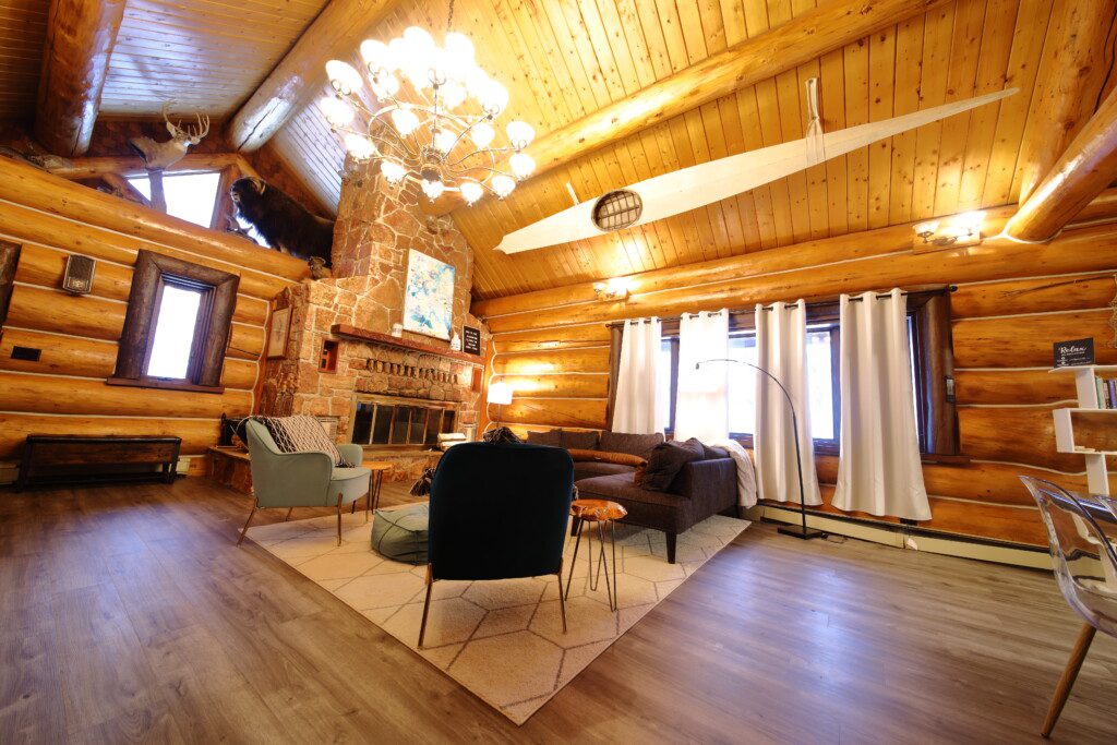 Cozy log cabin living room with stone fireplace, modern sofa, and wood carvings in Fairbanks Alaska
