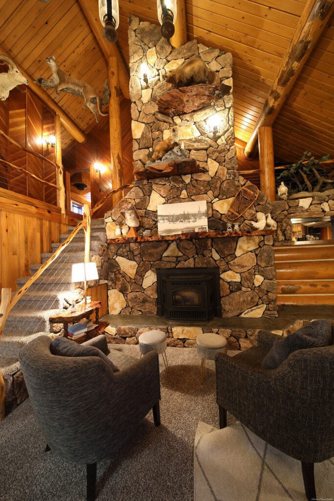 Cozy log cabin living room with stone fireplace, modern sofa, and wood carvings in Fairbanks Alaska
