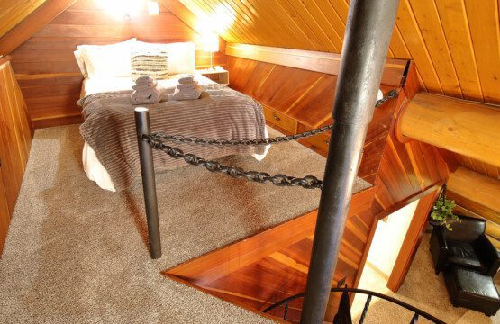 Rustic log cabin bedroom with cozy bedding and spiral staircase in Fairbanks Alaska