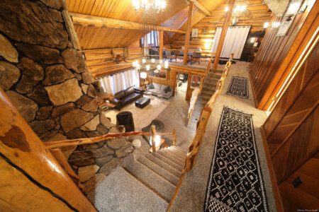 Cozy log cabin living room with stone fireplace, modern sofa, and wood carvings in Fairbanks Alaska
