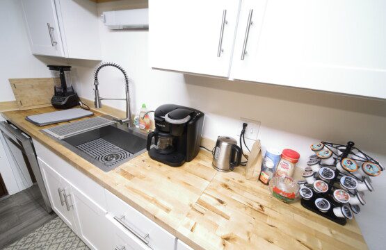 Bright rustic kitchen with white cabinets, wood countertops, and central island in a Fairbanks adventure lodge