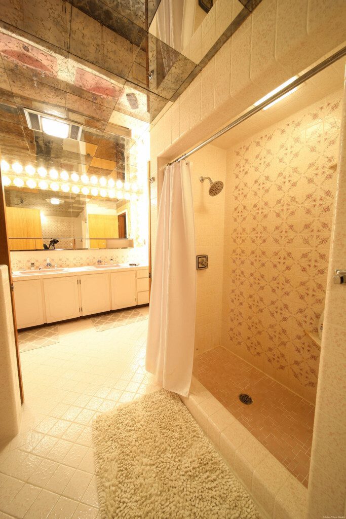 Retro-style bathroom with dual pink sinks, large mirrors, and warm vanity lighting in a Fairbanks Alaska lodge
