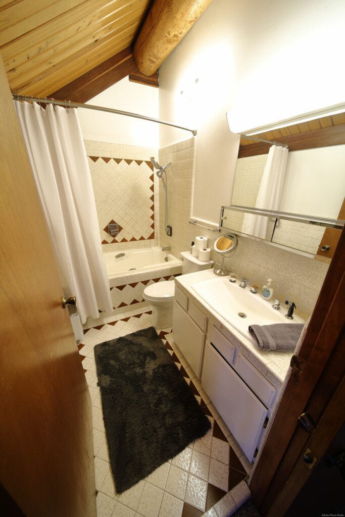 Warm cabin-style bathroom in Fairbanks Alaska with wooden ceiling, soaking tub, and tile floors