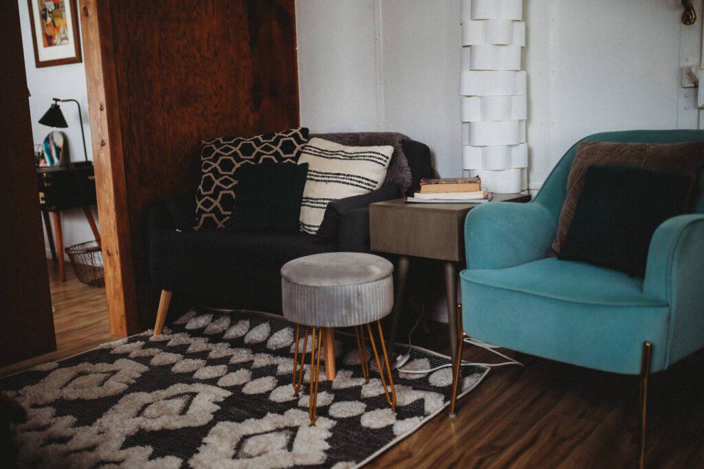 Modern seating nook with patterned pillows, teal armchair, and books in a Fairbanks Alaska treehouse rental