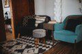 Modern seating nook with patterned pillows, teal armchair, and books in a Fairbanks Alaska treehouse rental