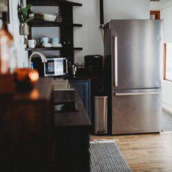 Stylish kitchen with stainless steel fridge, open shelves, and wood floors in a Fairbanks Alaska lodge