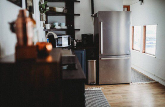 Stylish kitchen with stainless steel fridge, open shelves, and wood floors in a Fairbanks Alaska lodge