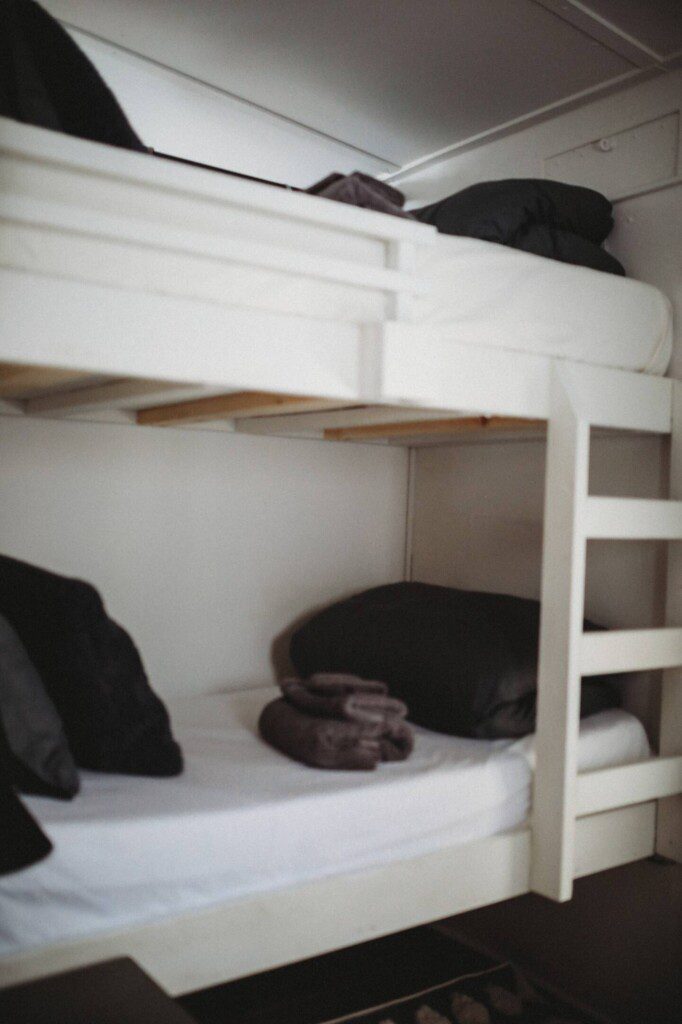 White wooden bunk beds with black pillows and folded towels in a Fairbanks Alaska adventure lodge