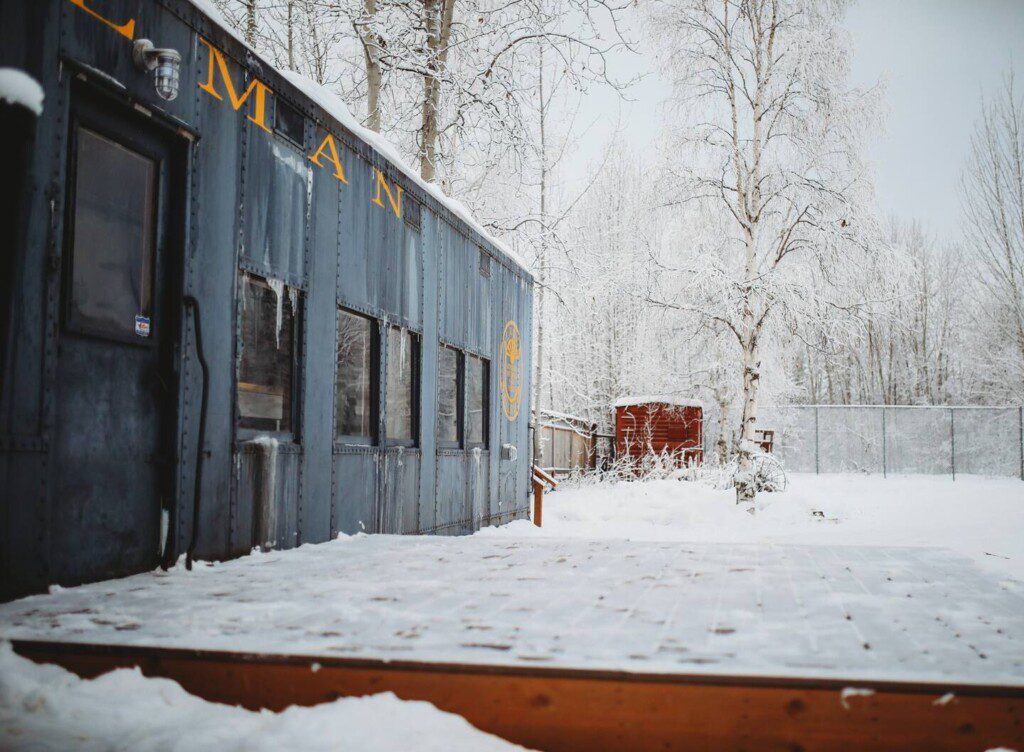 Historic railcar lodging with snowy deck and winter trees in Fairbanks Alaska