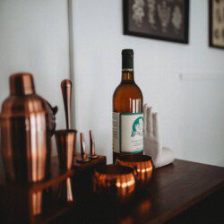 Bottle of alcohol with copper bar tools and mugs on a wooden counter in a Fairbanks Alaska lodge rental