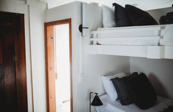 White bunk beds inside restored railcar at Alaska adventure lodge in Fairbanks.