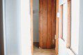 Narrow hallway with wooden door, white walls, and natural light in a Fairbanks Alaska adventure lodge