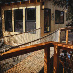 Couple standing on a snowy wooden treehouse deck surrounded by pine trees in Fairbanks Alaska