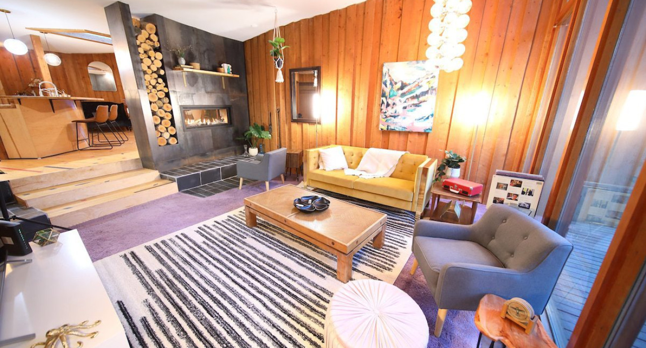 Mid-century modern living room with fireplace in a cozy Alaska treehouse rental near Fairbanks, ideal for weddings or getaways
