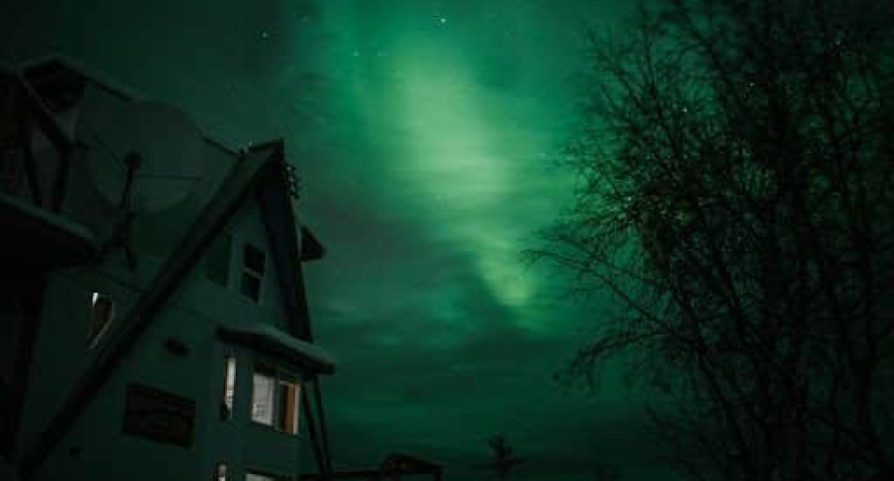 Treehouse-style rental in Fairbanks, Alaska illuminated by northern lights